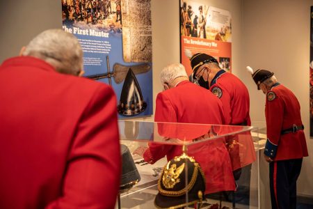 Veterans in red uniforms examining historical displays