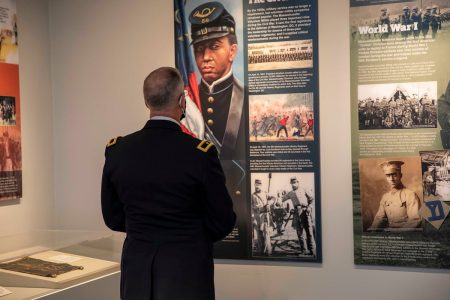 Man in uniform viewing historical military exhibit.